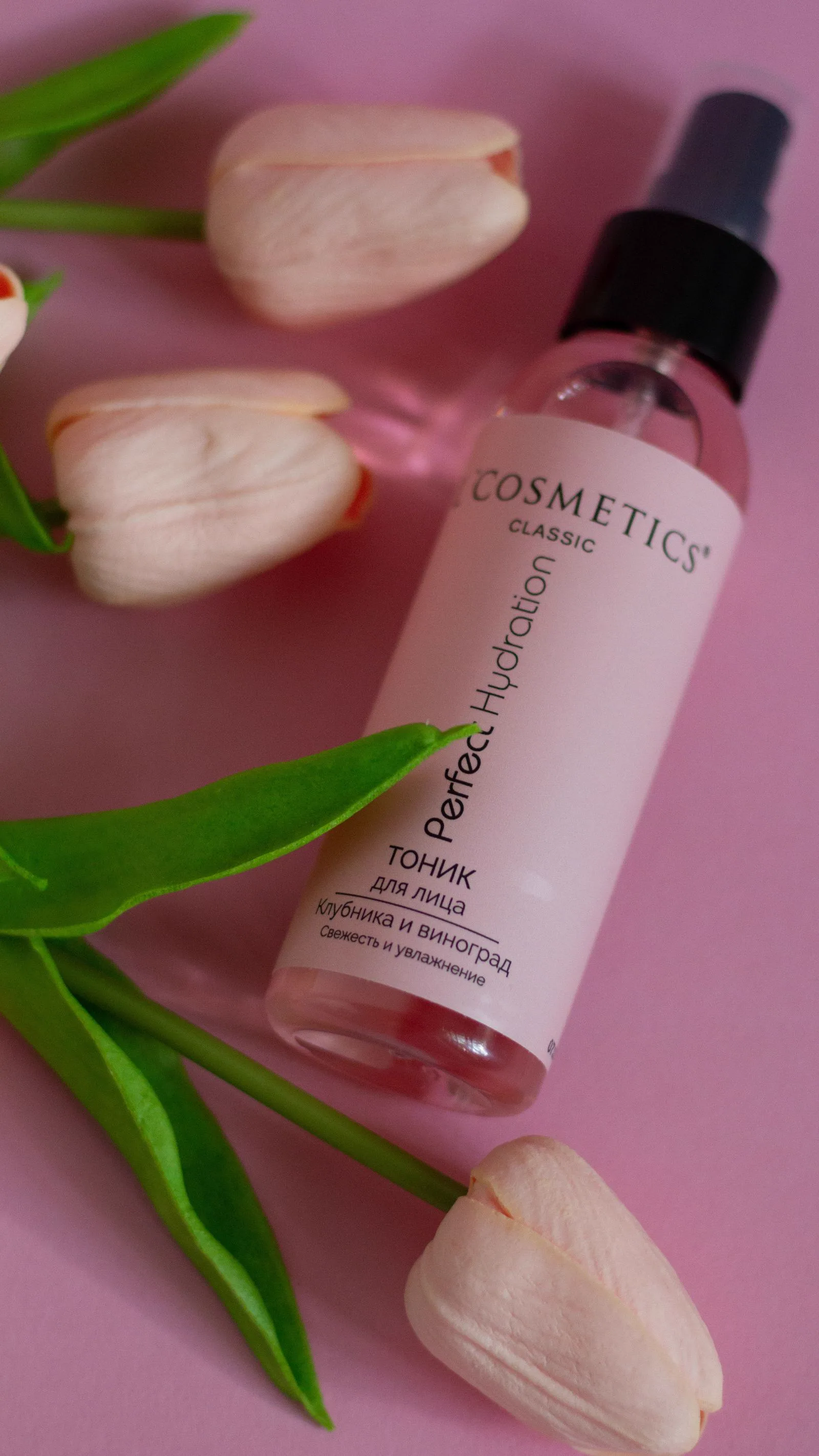 Producto de belleza con tulipanes sobre fondo rosa